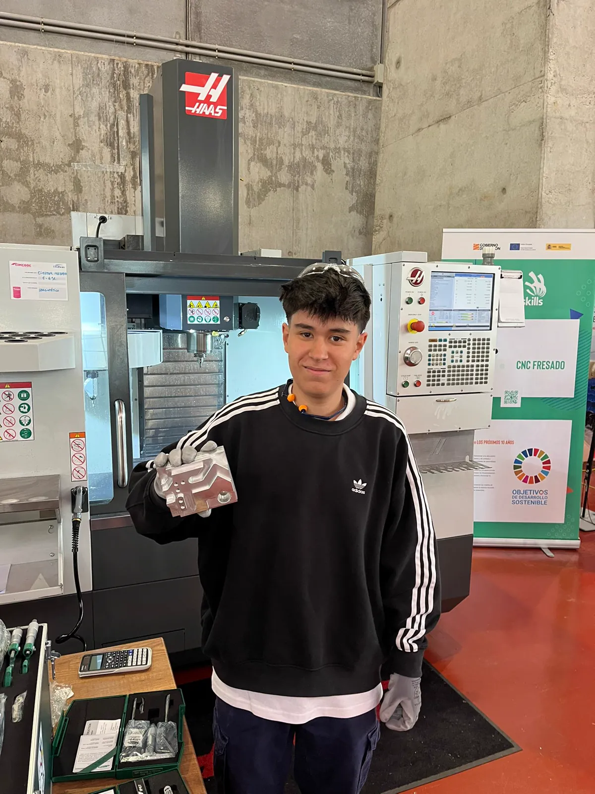 Ciro con una pieza mecanizada junto a un centro de mecanizado Haas en Aragón Skills 2025.