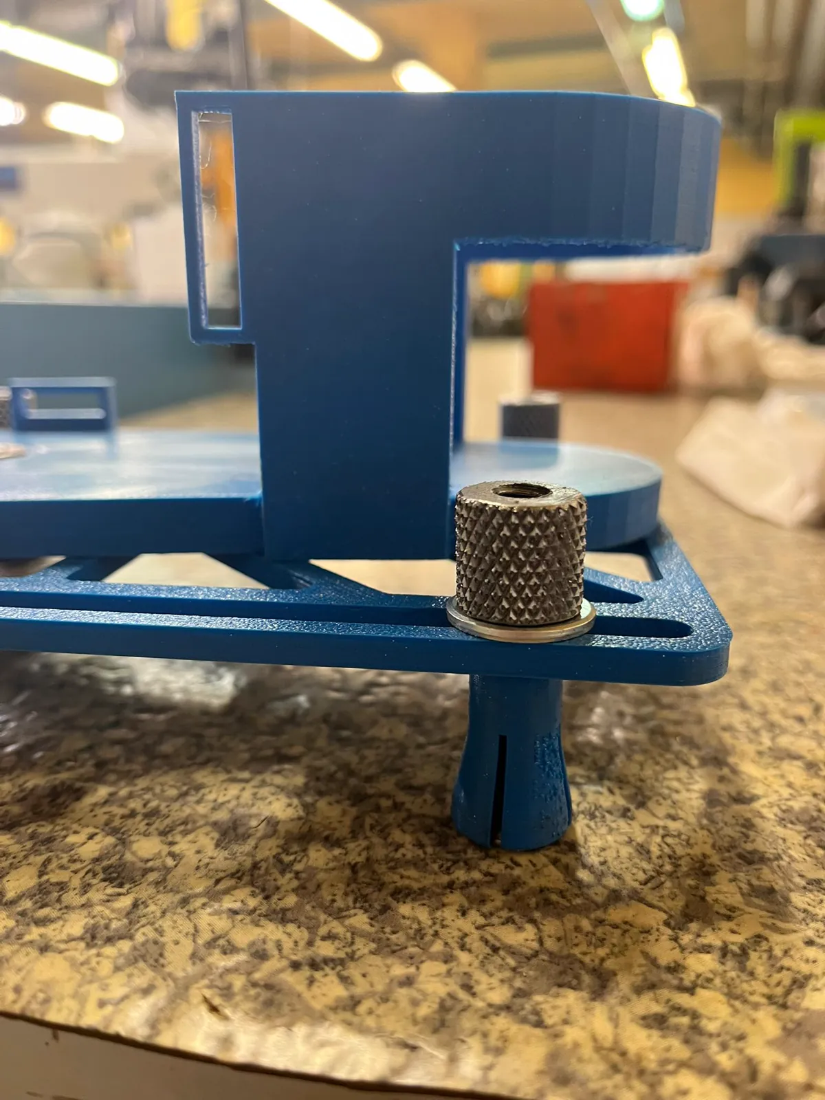 Pieza azul de sujeción con tornillo moleteado.