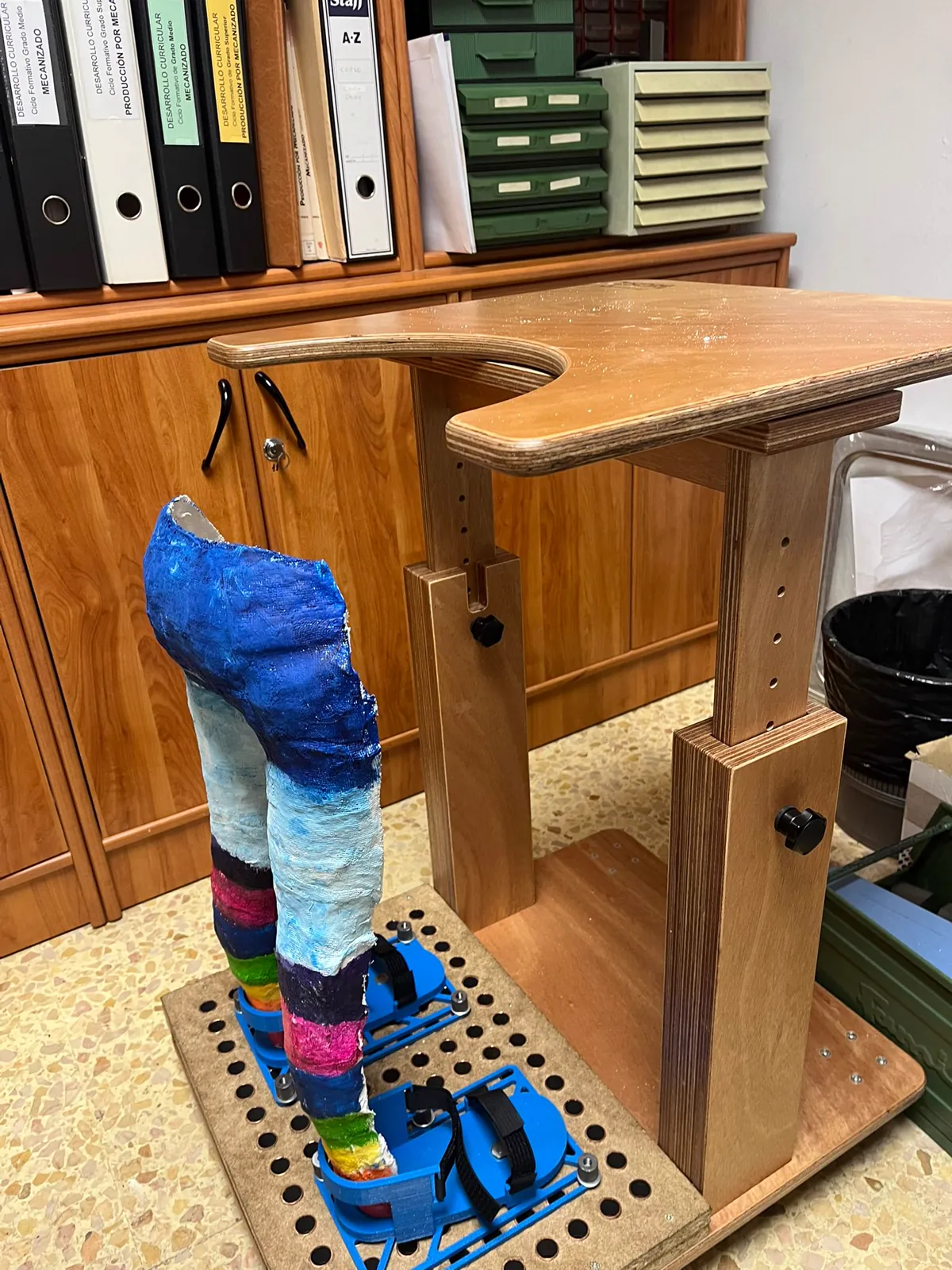 El bipedestador terminado: estructura de madera regulable con apoyos azules para los pies.