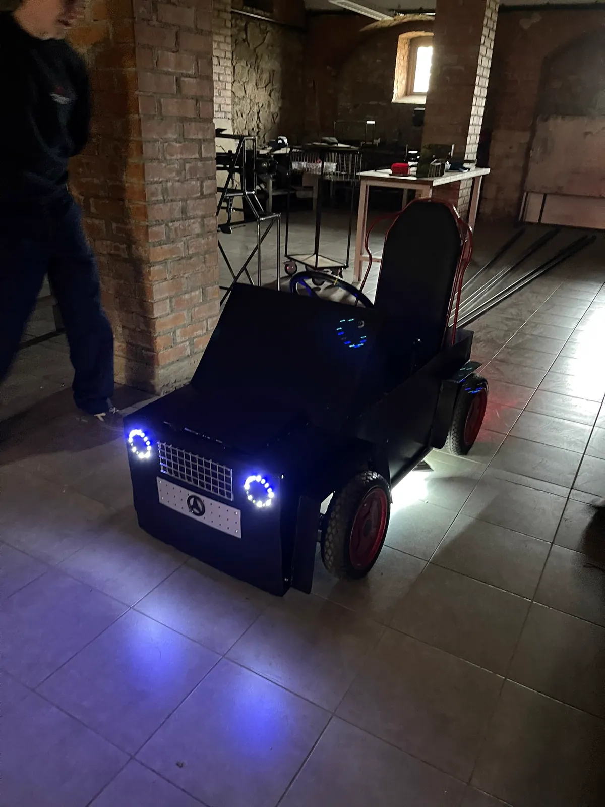 El e-buggy terminado, con carrocería negra y las luces encendidas.