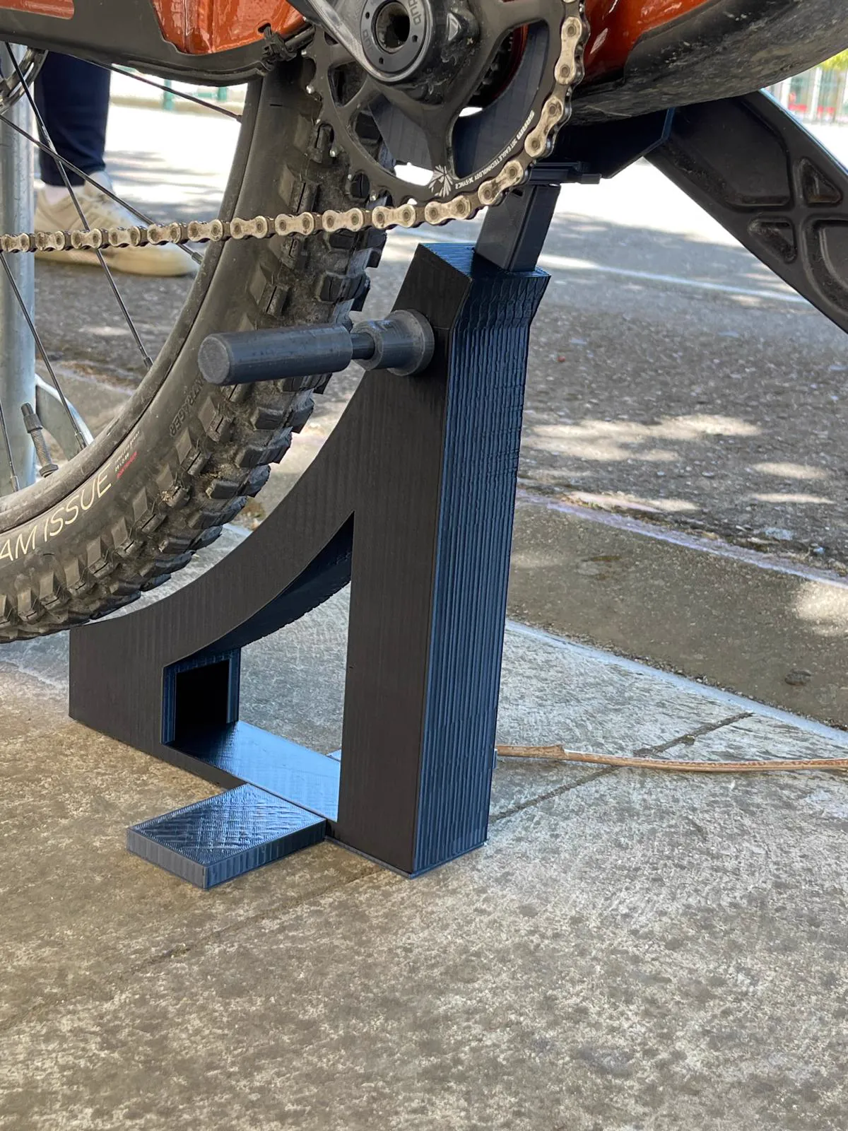 El soporte azul sujetando una bicicleta de montaña por la rueda trasera.