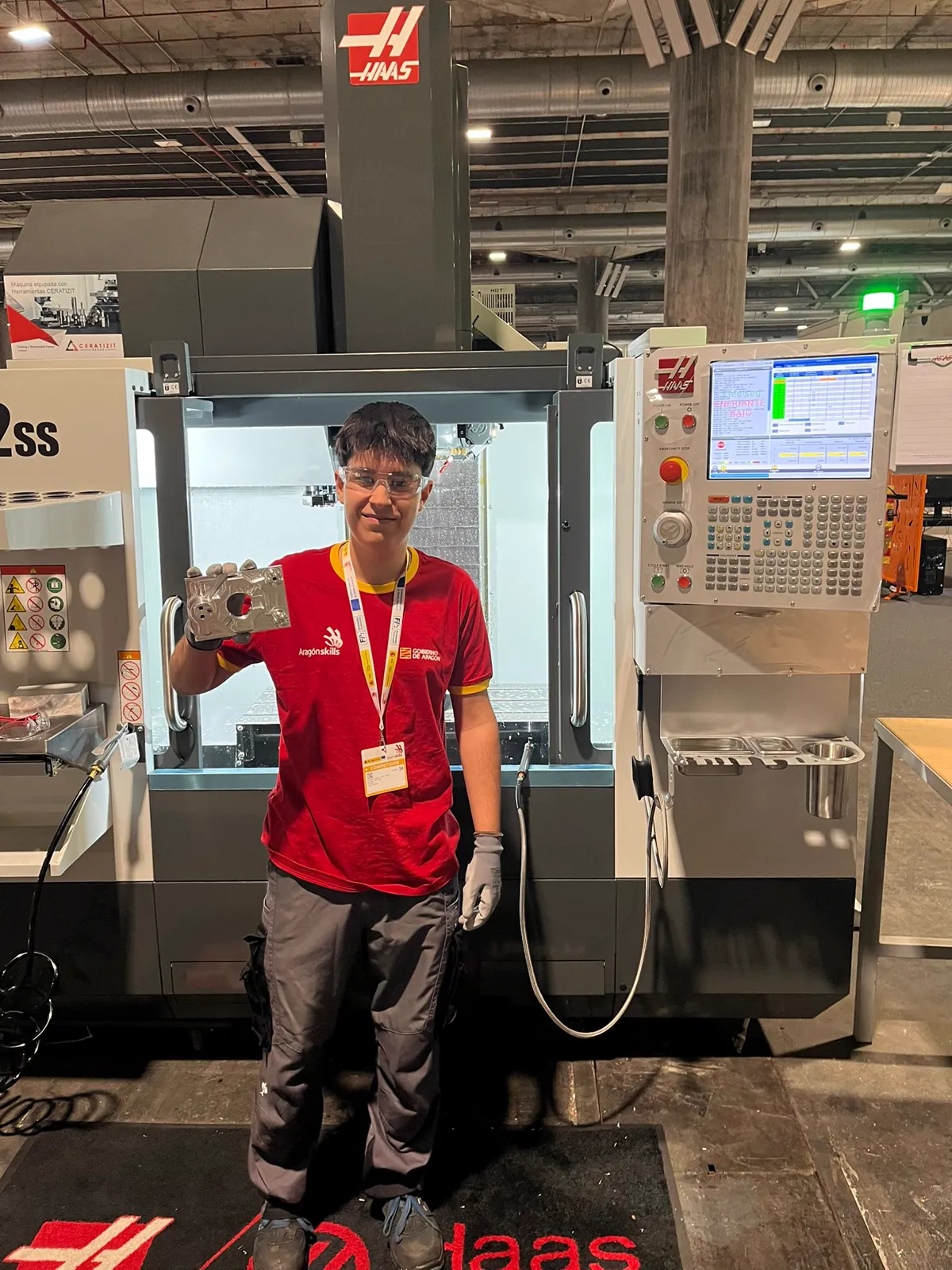 Ciro con una pieza mecanizada junto a un centro de mecanizado Haas en SpainSkills 2026.